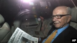 News Corp Chief Executive and Chairman Rupert Murdoch holds a copy of The Times newspaper as he leaves his home in London July 20, 2011