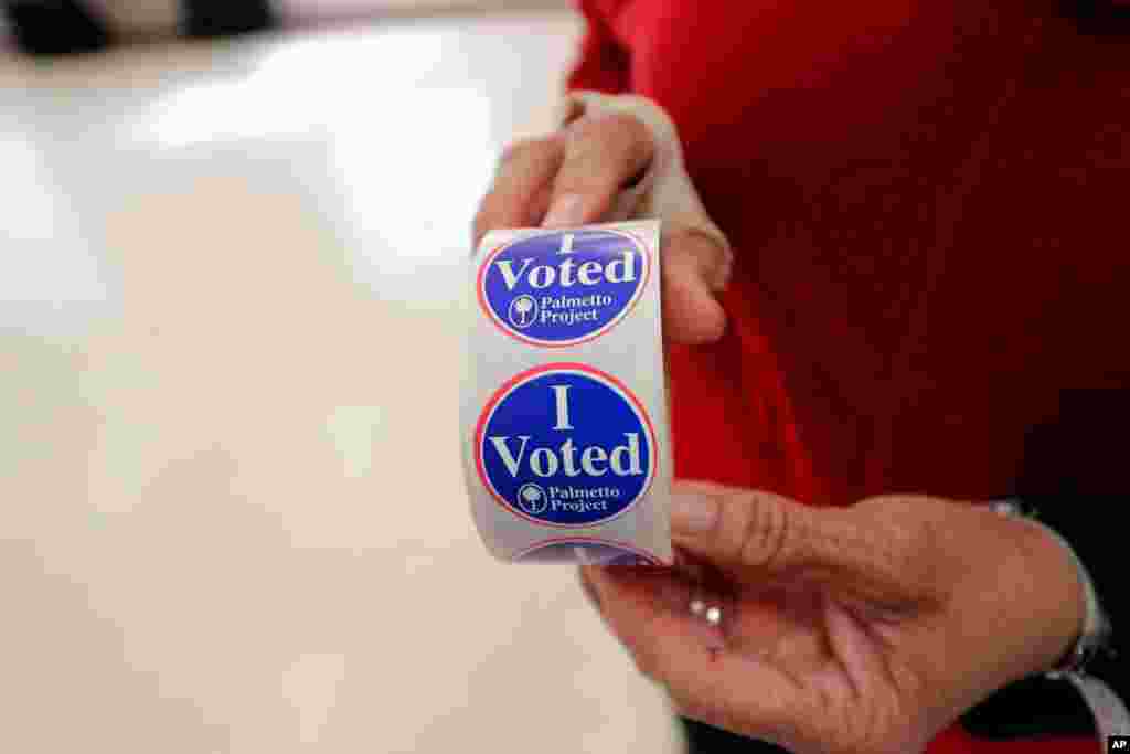 Polling manager Diana Belton shows a roll of voting stickers as people arrive to vote in the Democratic presidential primary in Hopkins, S.C., Feb. 29, 2020. 