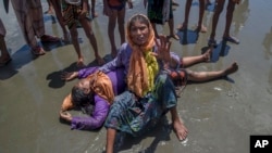 A Rohingya Muslim woman, who crossed over from Myanmar into Bangladesh, shouts for help as a relative lies unconscious after the boat they were traveling in capsized minutes before reaching shore at Shah Porir Dwip, Bangladesh, Thursday, Sept. 14, 2017. N