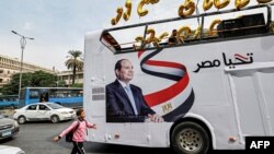 Seorang anak laki-laki berjalan di dekat bus kampanye milik tim pemenangan Presiden Mesir Abdel Fattah al-Sisi di wilayah Giza, Mesir, pada 2 Oktober 2023. (Foto: AFP/Khaled Desouki)