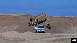 A excavator dumps bauxite ore into a dump truck at a mine belonging to China's Bosai Minerals Group in Linden, (File)