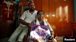 Karibeeran Paramesvaran and his wife Choodamani, who had lost three children in the 2004 tsunami, pose with a photograph showing their children inside their house that they have turned into a care home for orphaned children in Nagapattinam. (REUTERS/P. Ravikumar)