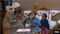 Meaza Takele reads the 'Tibeb Girls' comis strip to her young children.