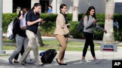 FILE - Students walk past a "Vote" sign next to an early voting site on the Florida International University campus, Oct. 23, 2018, in Miami. 