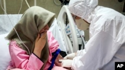 FILE - a medic wearing protective gear treats a patient infected with the new coronavirus, at Baqiyatallah Al'Azam Hospital affiliated to the Revolutionary Guard, in Tehran, Iran. 