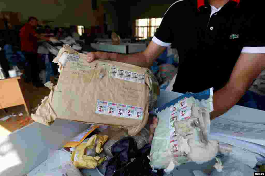 A Palestinian worker displays items sent by mail in the West Bank city of Jericho. Postal workers have been sorting through thousands of mail sacks for the past several days after Israeli authorities allowed the entry of the letters and packages from neighboring Jordan. The 10.5 tons of mail had been held in Jordan since 2010 because Israel would not permit direct transfer to the Palestinian Authority in the West Bank, Palestinian officials said.