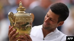 Novak Djokovic holds the winner's trophy after beating Matteo Berrettini during their men's singles final match on the thirteenth day of the 2021 Wimbledon Championships in Wimbledon, July 11, 2010. (Photo by Steven Paston/Pool/AFP)