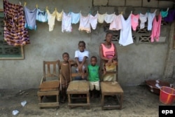 Victoria Topay and her children pose for a family portrait at her home in West Point, Monrovia, Liberia. The empty chairs are a symbolic representation of Victoria's late husband and family members who died of the Ebola virus, March 24, 2016.
