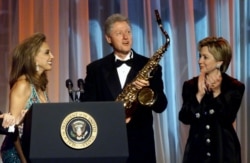 FILE - Denise Rich, left, ex-wife of Marc Rich, presents U.S. President Bill Clinton with a saxophone as first lady Hillary Rodham Clinton applauds at the G&P Foundation gala in New York City, Nov. 30, 2000.