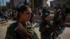 Kurdish soldiers stand guard at a rally in support of the Kurdish forces, in Qameshli, Syria, Oct. 23, 2019. (Yan Boechat/VOA)