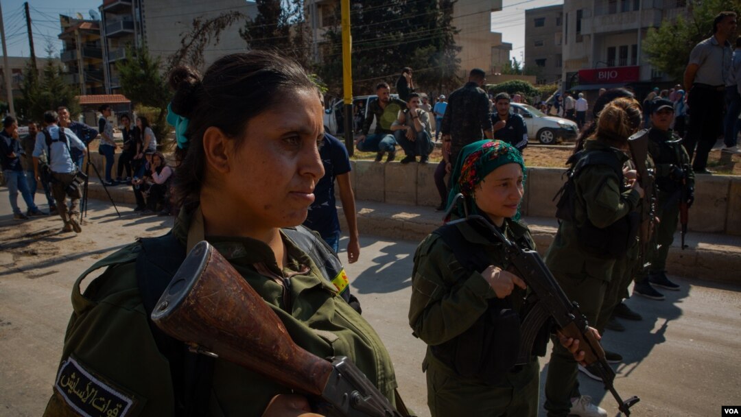 Kurdish soldiers stand guard at a rally in support of the Kurdish forces, in Qameshli, Syria, Oct. 23, 2019. (Yan Boechat/VOA)
