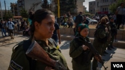 Kurdish soldiers stand guard at a rally in support of the Kurdish forces, in Qameshli, Syria, Oct. 23, 2019. (Yan Boechat/VOA)