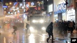 Demostran berlarian saat polisi anti huru-hara membubarkan aksi mereka dengan meriam air di Istanbul, Turki (27/12).