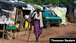 Una mujer camina con ayuda de un palo en el campamento de personas internamente desplazadas de Kuchingoro mientras el gobierno sigue tratando de detener los contagios del COVID-19, en Abuja, Nigeria. Junio 20, 2020.