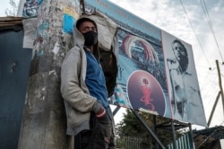FILE - A young man stands in front of a sign of the Tigray People’s Liberation Front (TPLF) party, in the city of Mekele, northern Ethiopia, Sept. 6, 2020.