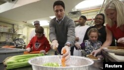 FILE - Liberal leader Justin Trudeau helps prepare Thanksgiving dinner with his son Xavier, bottom left, and daughter Ella-Grace, bottom right, at the Salvation Army in Ottawa, Ontario, Oct. 11, 2015.
