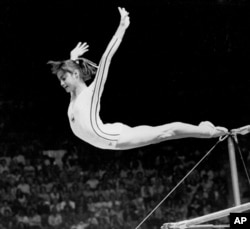 Romania's Nadia Comaneci dismounts from the uneven parallel bars to score a perfect 10.00 in the Women's Gymnastic Olympic competition in Montreal, July 18, 1976. (AP Photo/Suzanne Vlamis)