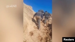 FILE - Hamas militants scale a hill a at a location given as Juhr Al-Dik, Gaza, in this still image from video said to be from Dec. 15, 2023. Some Chinese vloggers depict Hamas as heroic and capable on the battlefield. Hamas Military Wing via REUTERS 