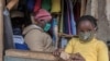 FILE - A woman who trades in fabrics, and her child, wears face masks as preventive measure against the COVID-19 coronavirus, in her shop inside Lilongwe City market in Lilongwe on May 18, 2020.
