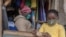 FILE - A woman who trades in fabrics, and her child, wear face masks to rotect against the coronavirus, in her shop inside Lilongwe City market, in Lilongwe, Malawi, May 18, 2020. 