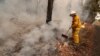 Seorang petugas pemadam kebakaran memindahkan puing-puing yang terbakar dalam upaya memadamkan api di dekat Burrill Lake, Australia, Minggu, 5 Januari 2020. (AP Photo / Rick Rycroft)