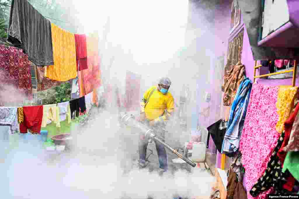 A municipal worker fumigates a slum area as a preventive measure against mosquito-born diseases in Kolkata, India.
