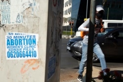 A pedestrian walks past a sign pasted on a sidewalk in Johannesburg, South Africa, Tuesday, Aug. 18, 2020. Millions of women and girls globally have lost access to contraceptives, abortion services and related care because of the coronavirus pandemic. (AP)