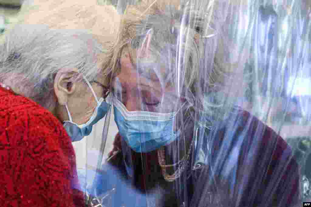 A resident (L) of the Domenico Sartor nursing home in Castelfranco Veneto, near Venice, Italy, hugs her visiting daughter through a plastic screen in a so-called "Hug Room" amid the COVID-19 pandemic.