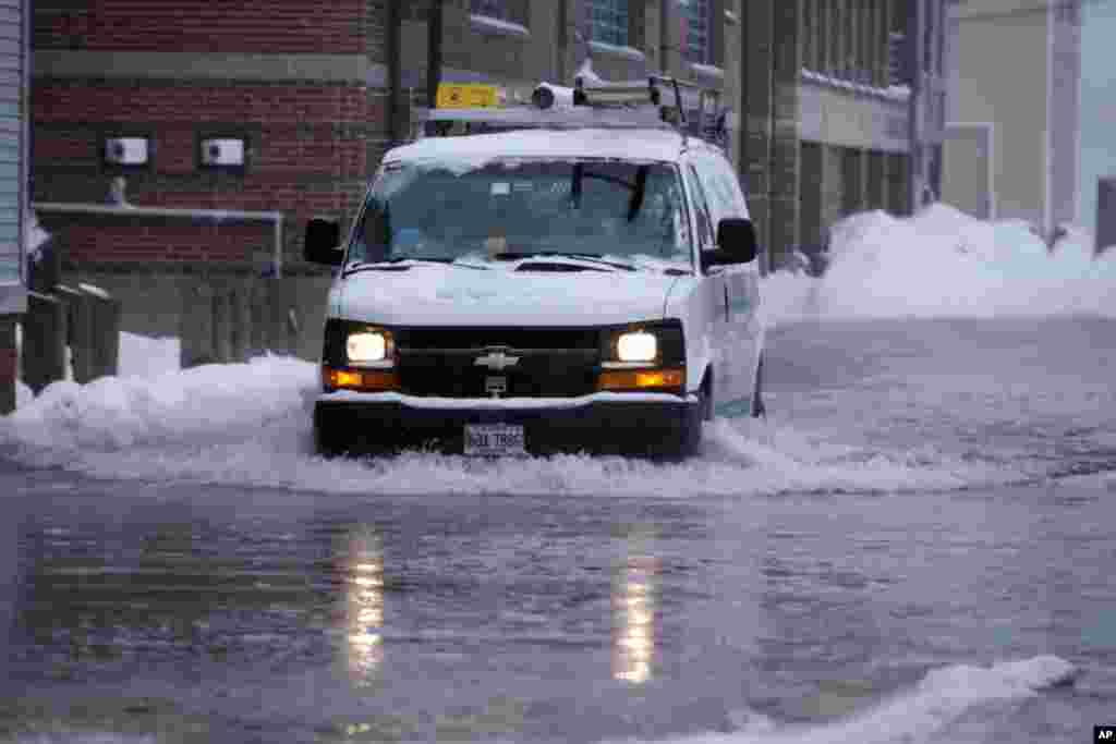 Sebuah truk melintasi banjir yang menggenangi sebuah jalan di Portland, negara bagian Maine, Kamis (2/1). (AP/Robert F. Bukaty)
