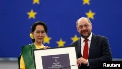 Burma's pro-democracy leader Aung San Suu Kyi (L) holds her 1990 Sakharov Prize, besides European Parliament President Martin Schulz, during an award ceremony in Strasbourg, France, Oct. 22, 2013.