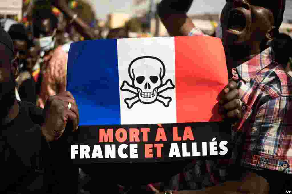 Demonstrators hold up a sign that reads "Death to France and its allies," during a mass demonstration to protest sanctions imposed on Mali and the Junta, by the Economic Community of West African States (ECOWAS), in Bamako.