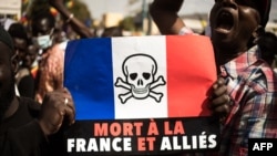 Demonstrators hold up a sign that reads "Death to France and its allies," during a mass demonstration to protest sanctions imposed on Mali and the Junta, by the Economic Community of West African States (ECOWAS), in Bamako.