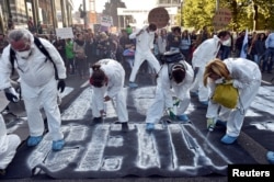 Greenpeace activists spray-painted “No TTIP” and “No CETA” on the roads as thousands of people demonstrate in the center of Brussels, Belgium, Sept. 20, 2016.