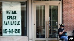 A woman looks at her phone outside of a rental sign displayed at a store in Deerfield, Ill., June 11, 2020.