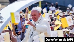 Pope Francis waves to faithful holding Vatican flags as he arrives on his pope-mobile to celebrate a Byzantine rite Mass at Mestska sportova hala Square, in Presov, Slovakia, Sept. 14, 2021. (AP Photo/Darko Vojinovic)