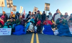 Demonstrators gather to block a road at the base of Hawaii's tallest mountain, July 15, 2019, in Mauna Kea, Hawaii, to protest the construction of a giant telescope on land that some Native Hawaiians consider sacred.