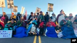 Demonstrators gather to block a road at the base of Hawaii's tallest mountain, Monday, July 15, 2019, in Mauna Kea, Hawaii, to protest the construction of a giant telescope on land that some Native Hawaiians consider sacred. 