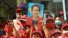 Myanmar migrants hold up portraits of detained leader Aung San Suu Kyi as they rally outside Myanmar's embassy in Bangkok, Thailand, Feb. 1, 2021.