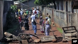Residents of the mostly Peul suburb of Bambeto, Conakry, walk back to their homes behind barricades they set after a shooting incident, 17 Nov 2010