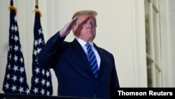 FILE PHOTO: U.S. President Donald Trump poses without face mask as he returns to the White House after being hospitalized at Walter Reed Medical Center for coronavirus disease (COVID-19), in Washington