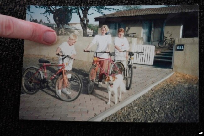 In this photo provided by Donna Dickinson, she poses with her brothers Steve, left, and Garry, right, and their dog Murphy in 1992 outside their home in Jebel Ali Village in Dubai, United Arab Emirates. (Courtesy of Donna Dickinson via AP)