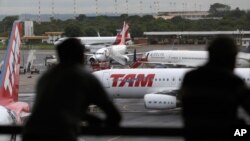 FILE - People look at jetliners at the Brasilia international airport, in Brasilia, Brazil, Nov. 28, 2013 