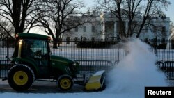 Des travailleurs labourent la neige du trottoir en face de la Maison Blanche à Washington, le 21 janvier 2016. (REUTERS/Jonathan Ernst - RTX23E67)