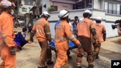 Emergency rescue teams recover the body of a victim in the heavy rains, Monday, July 9, 2018, in Hiroshima, Japan. (AP Photo/Haruka Nuga)