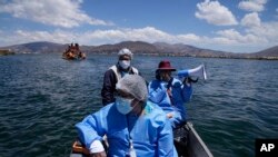 Para petugas medis menaiki perahu sambil membawa tas pendingin berisi vaksin COVID-19 dalam rangka program vaksinasi dari pintu ke pintu bagi masyarakat di area Danau Titicaca, di Puno, Peru, pada 27 Oktober 2021. (Foto: AP/Martin Mejia)