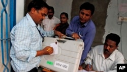 An election officer signs a piece of paper on an electronic voting machine before submitting it at a strong room in Kandhamal district, in the eastern Indian state of Orissa, April 10, 2014