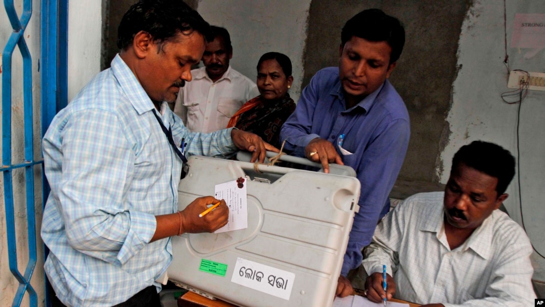 An election officer signs a piece of paper on an electronic voting machine before submitting it at a strong room in Kandhamal district, in the eastern Indian state of Orissa, April 10, 2014