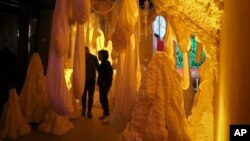 This Nov. 2, 2018 photo shows Kareem Rahma, right, founder and CEO of the Nameless Network and co-creator of The Museum of Pizza appears in an art installation in New York. (AP Photo/Bebeto Matthews)