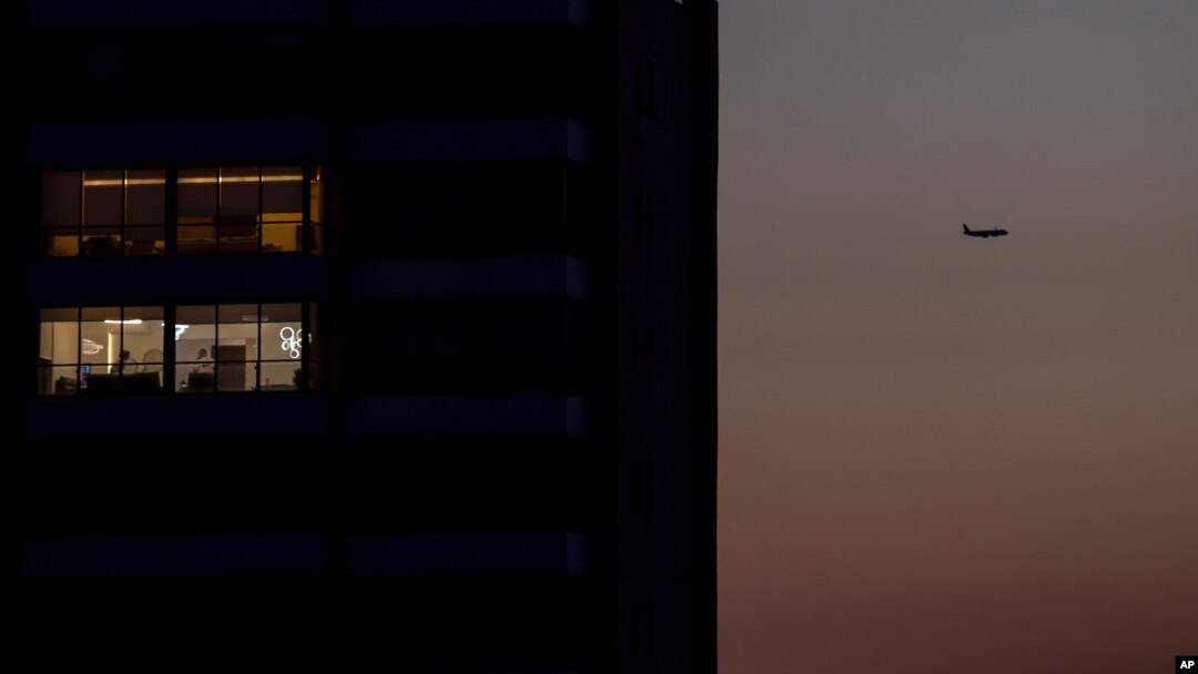 FILE - A passenger plane flies over Beirut, Lebanon, a capital in darkness because of a power outage, March 29, 2021.