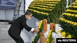 Japan's Prime Minister Yoshihide Suga wearing a protective face mask, places a wreath on the cenotaph for the victims on the 76th anniversary of the world's first atomic bombing in Hiroshima, Japan, August 6, 2021.